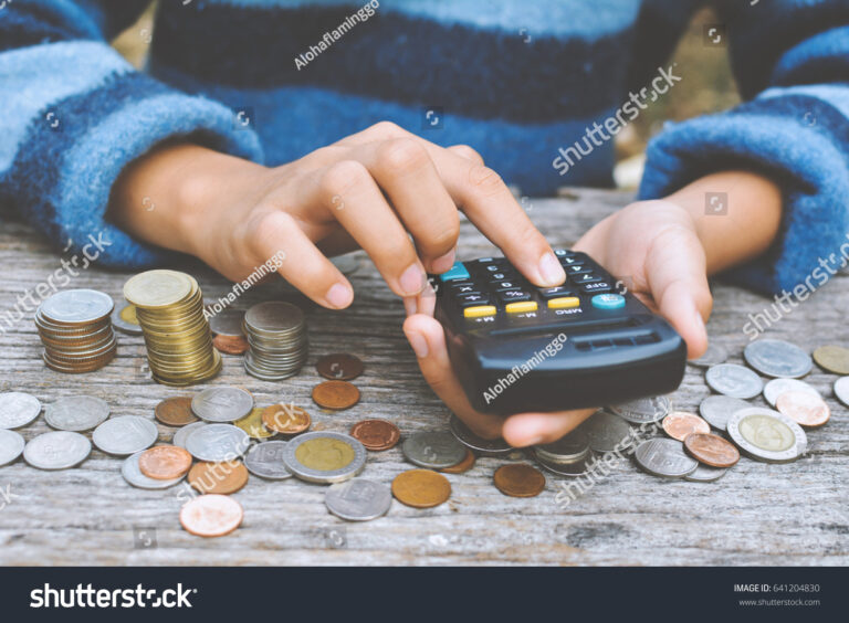 manos sosteniendo calculadora y monedas